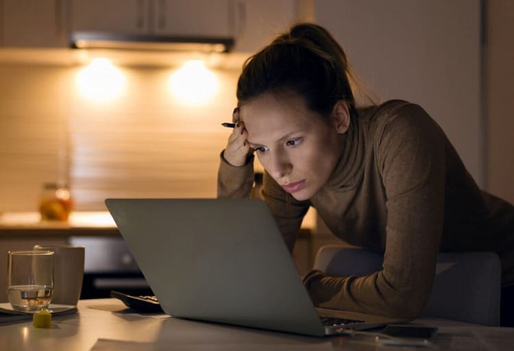 Erschöpfte Frau am Laptop fragt sich Jobwechsel ja oder nein und sucht nach Motivationscoaching Angeboten.